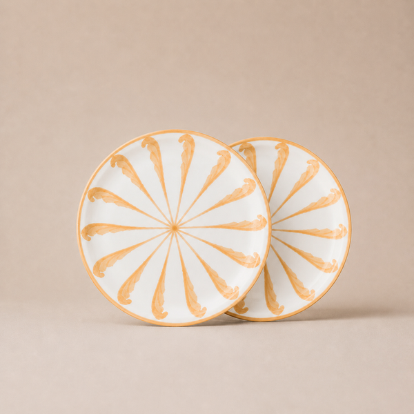 Two ceramic plates with gold decorative patterns on a beige background