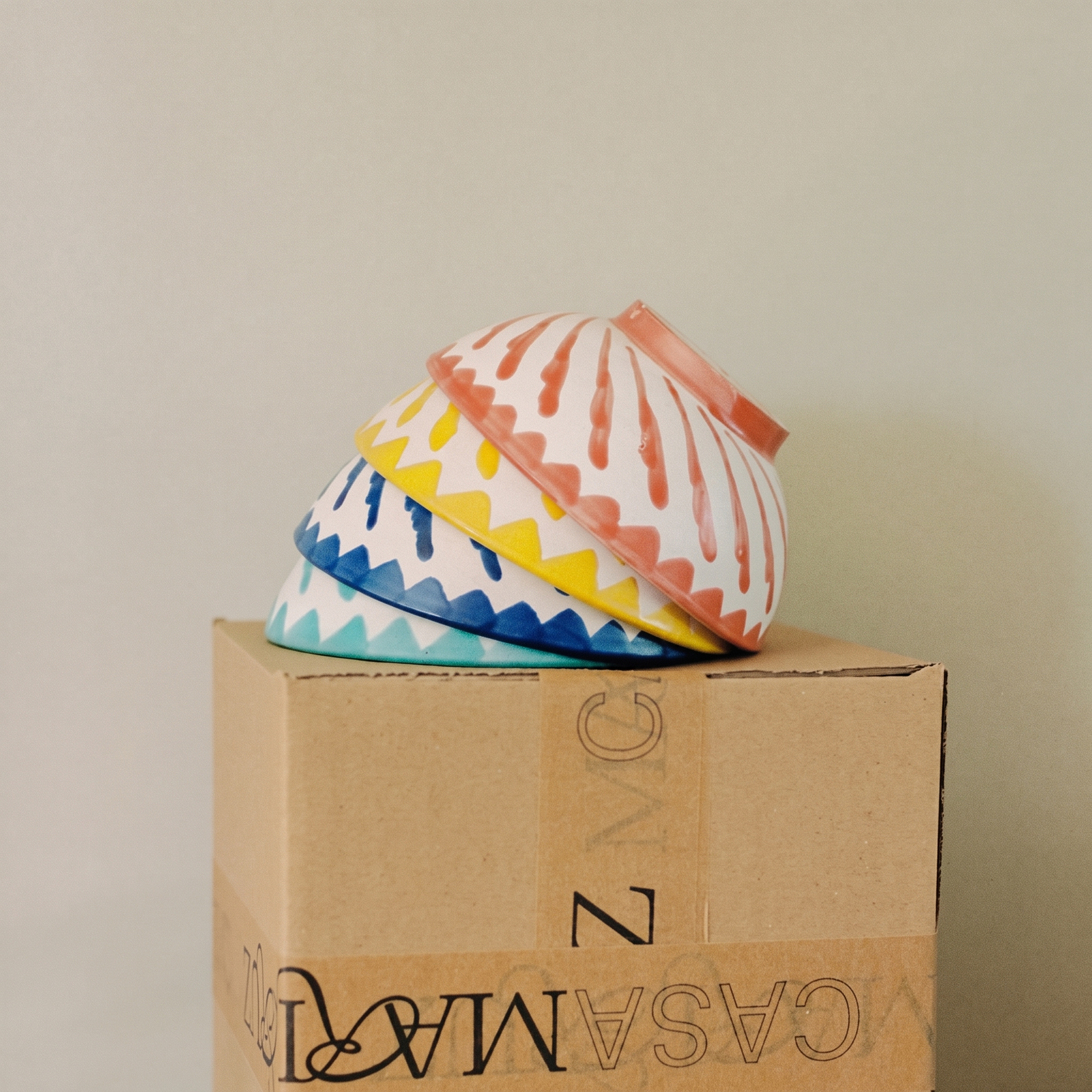 set of turquoise, blue, yellow and coral cereal bowls on top of a box - lifestyle
