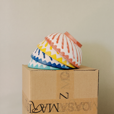 set of turquoise, blue, yellow and coral cereal bowls on top of a box - lifestyle