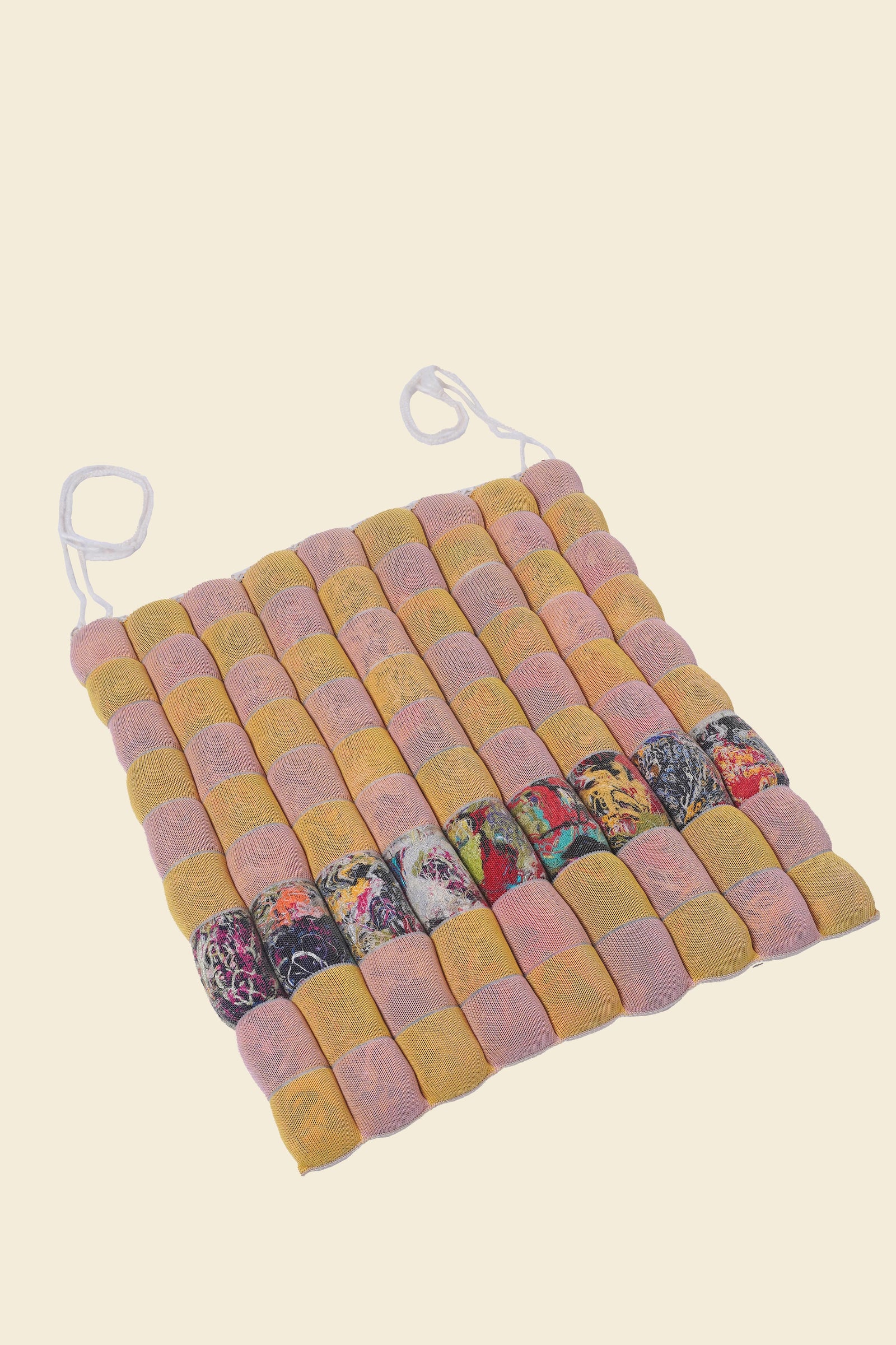 front view of yellow/pink knit checkered seat cushion with upcycled materials with beige background 