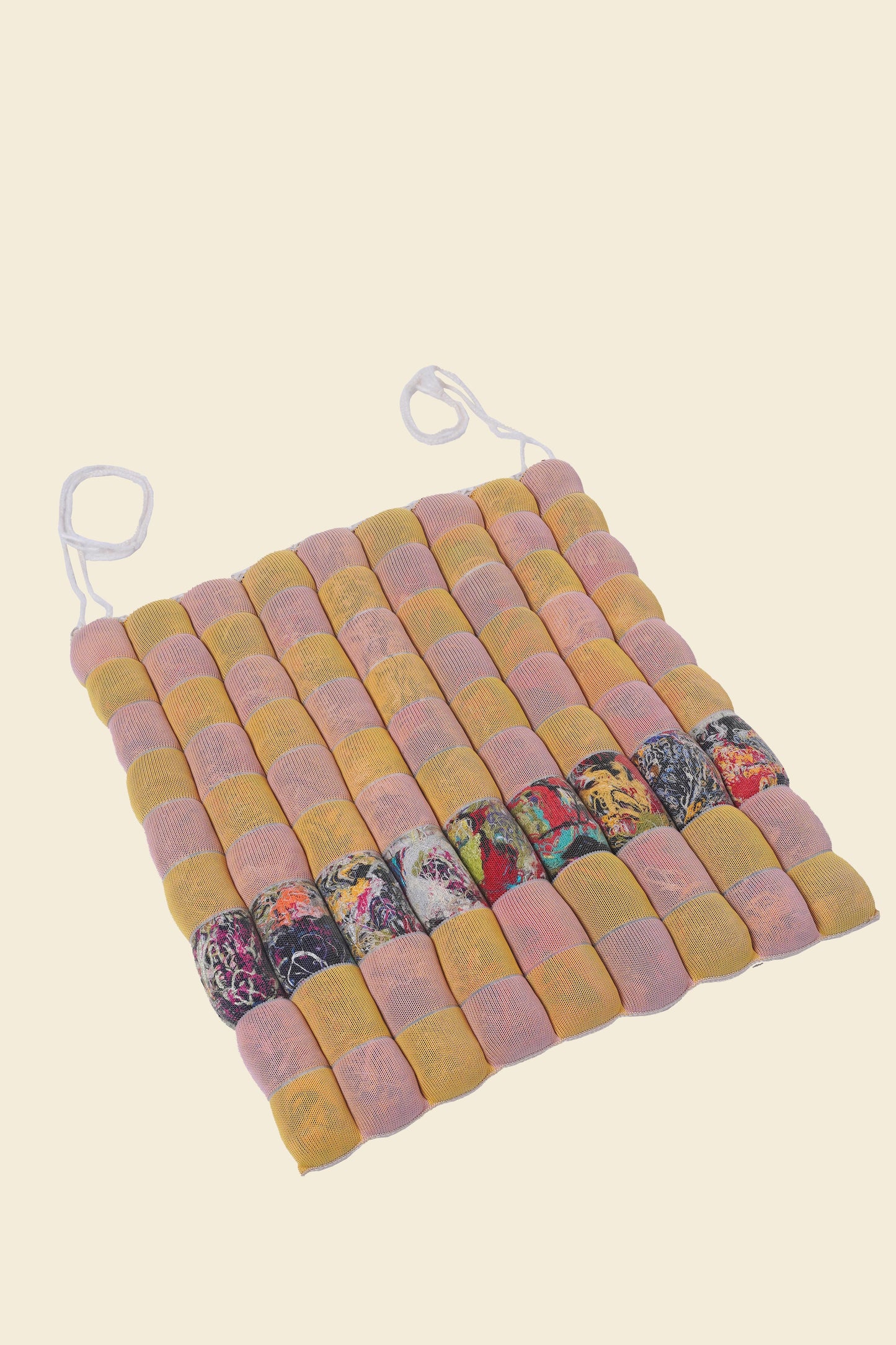 front view of yellow/pink knit checkered seat cushion with upcycled materials with beige background 