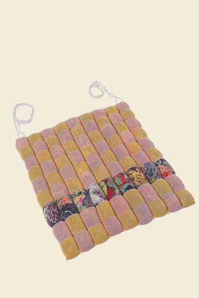 front view of yellow/pink knit checkered seat cushion with upcycled materials with beige background 
