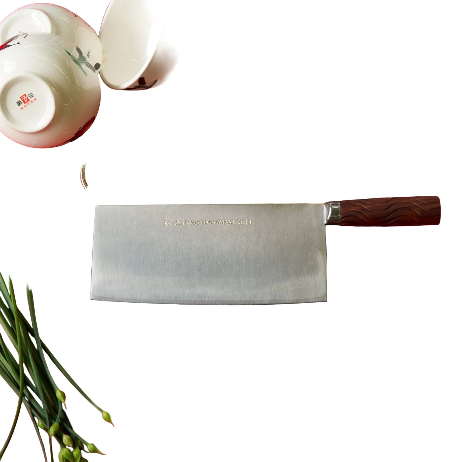 Wooden cutting board with a cleaver on a red tablecloth, surrounded by kitchen items.