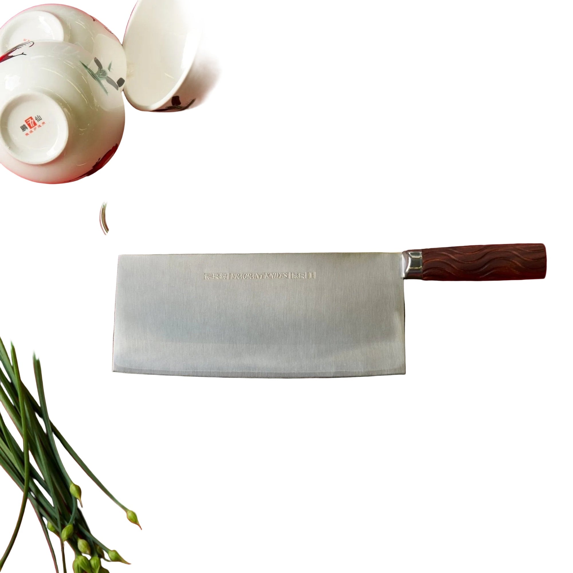 Wooden cutting board with a cleaver on a red tablecloth, surrounded by kitchen items.