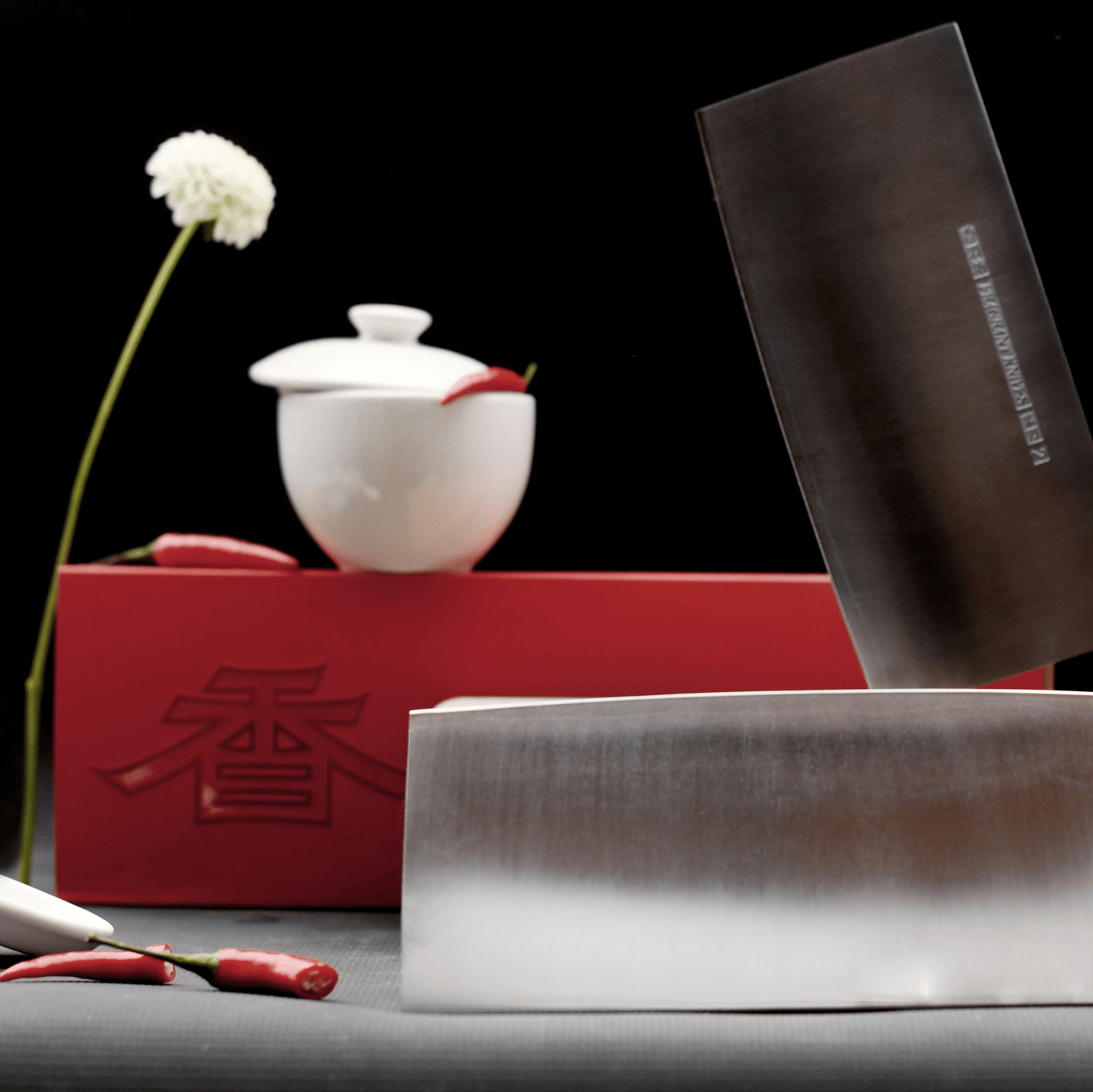 Chinese chef's knife with packaging and chilies, and allium plant.