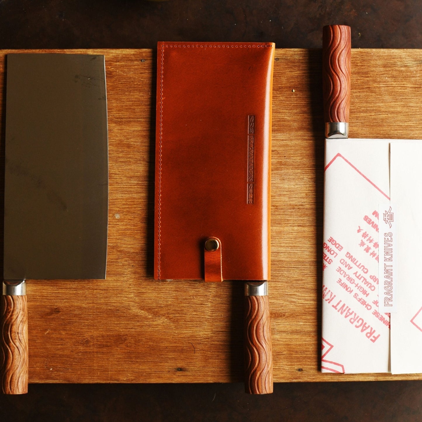 Three knives with sheaths on a wooden cutting board