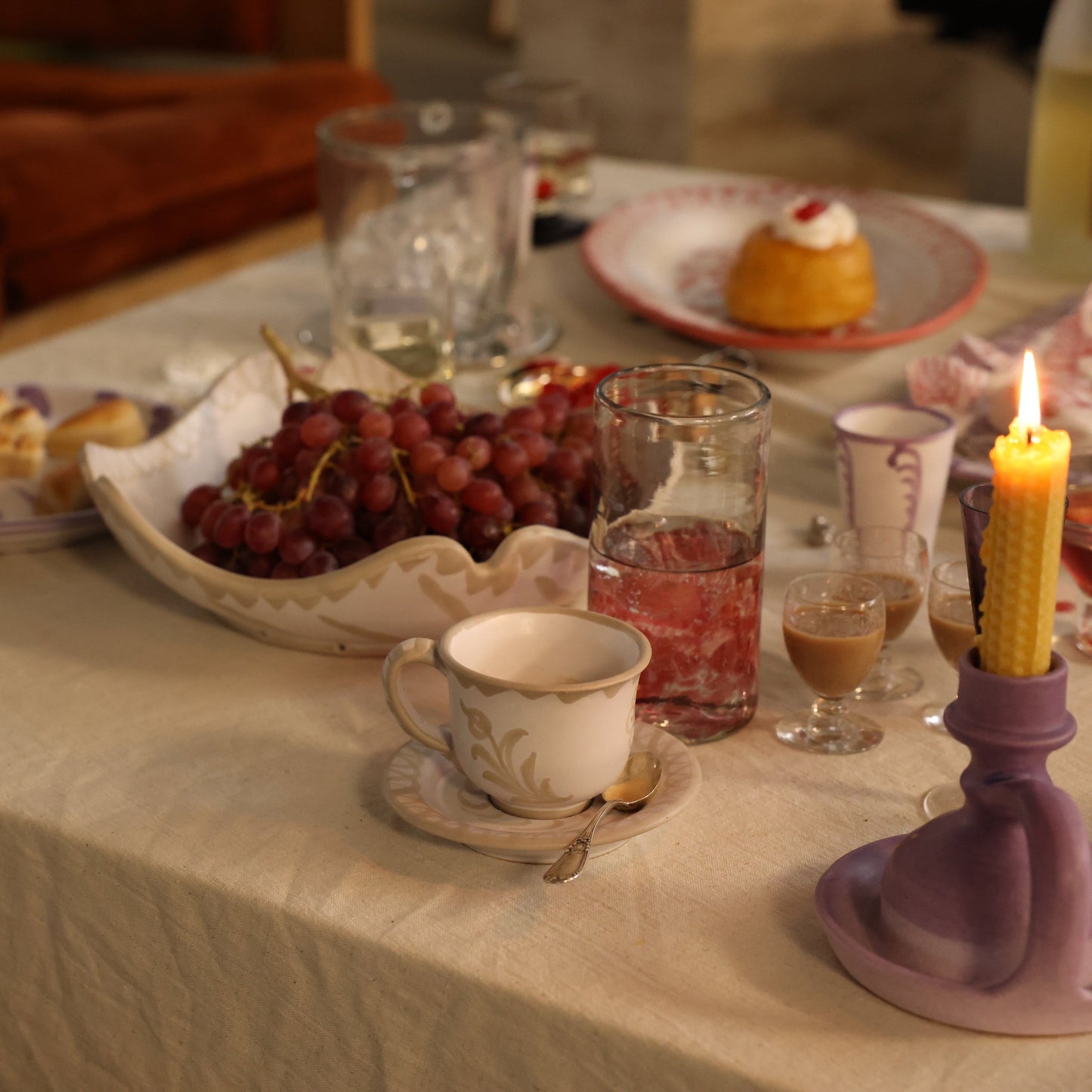 Table setting with tea cup, grapes, and candles in a cozy indoor setting - lifestyle