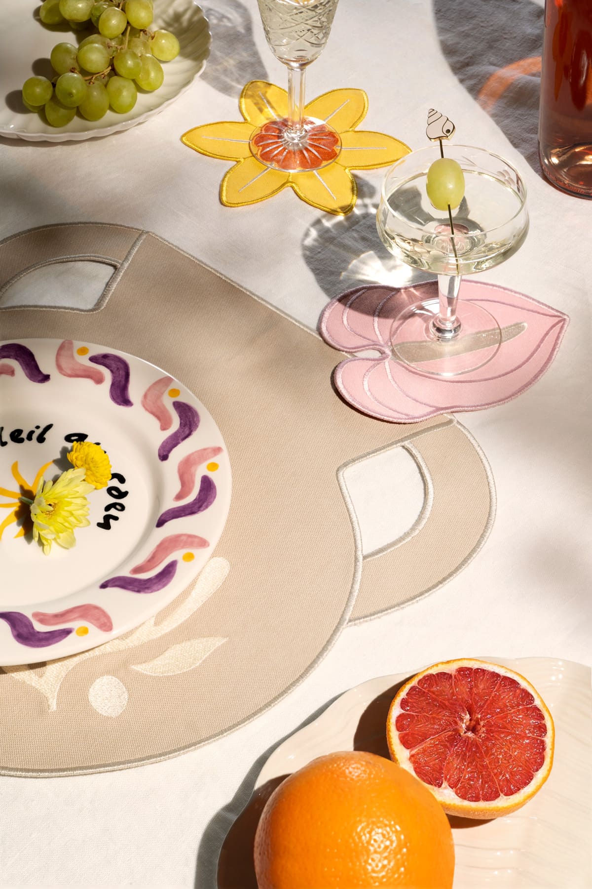 A table set with fruit and cocktails, featuring Octaevo’s Clay Amphora Placemats (Set of 2) as decor.