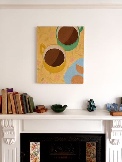 Oil painting of two cups of coffee on a yellow table cloth - seen hung on a wall