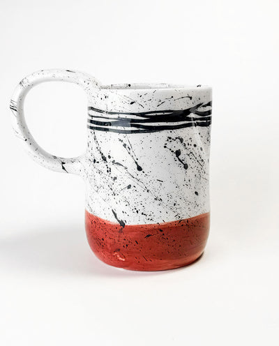 Greek Ceramic carafe with black splash design and red base on a white background