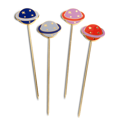 The Cosmos Cocktail Picks by Octaevo feature 4 gold-plated picks with colorful, starry UFO planet designs.