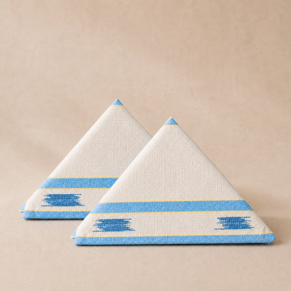 Two triangular napkins with blue and yellow patterns on a beige background