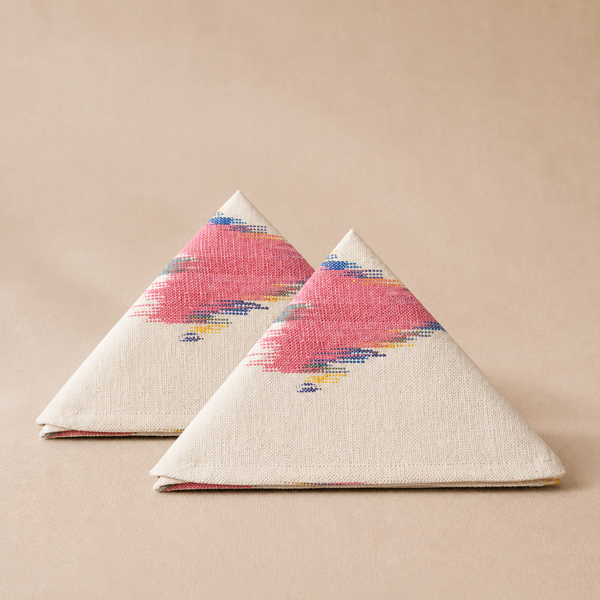 Two triangular napkins with pink and blue abstract patterns on a beige background