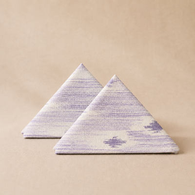 Two triangular napkins with a purple and white pattern on a beige background