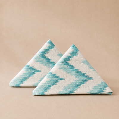 Two triangular napkins with a blue and white pattern on a beige background