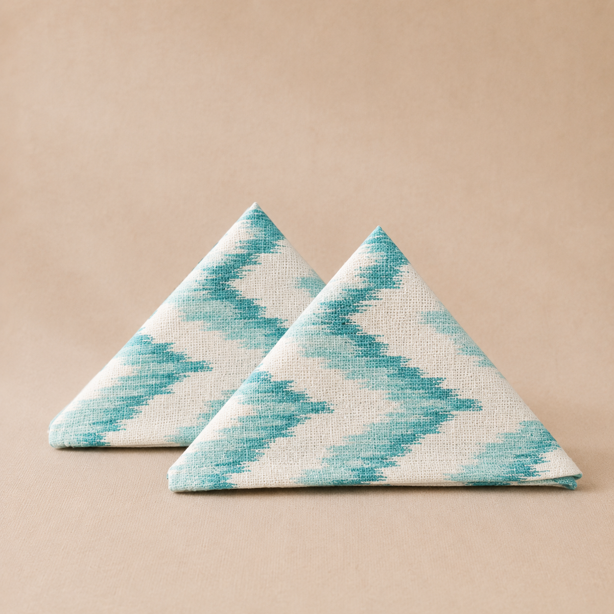 Two triangular napkins with a blue and white pattern on a beige background