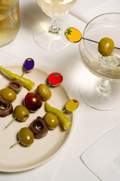 Octaevo Dolce Vita Cocktail Picks (Set of 4) displayed with olives, anchovies, peppers, and a cherry tomato.
