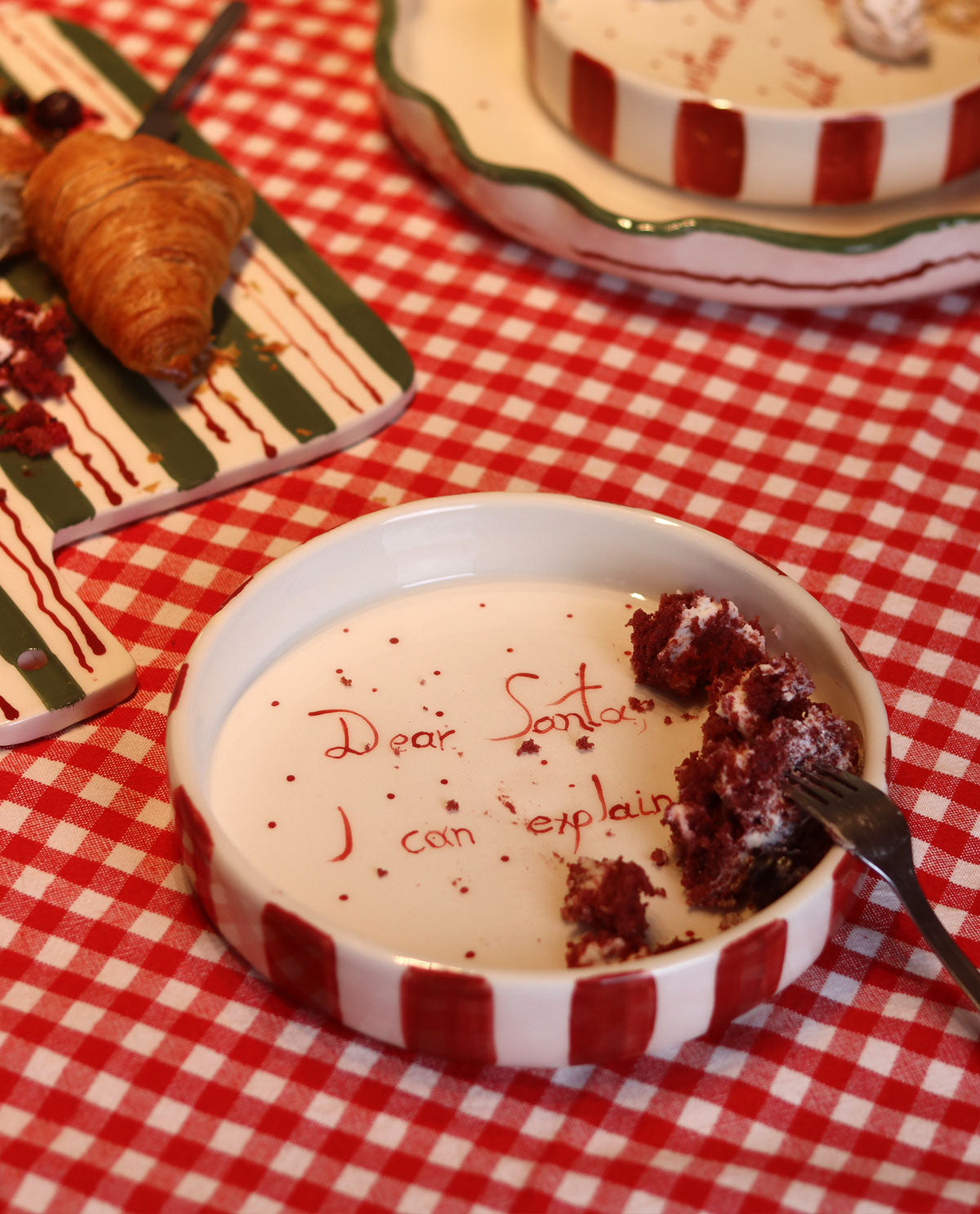 Red and white ceramic plate with a message to Santa, on a red and white checkered tablecloth.
