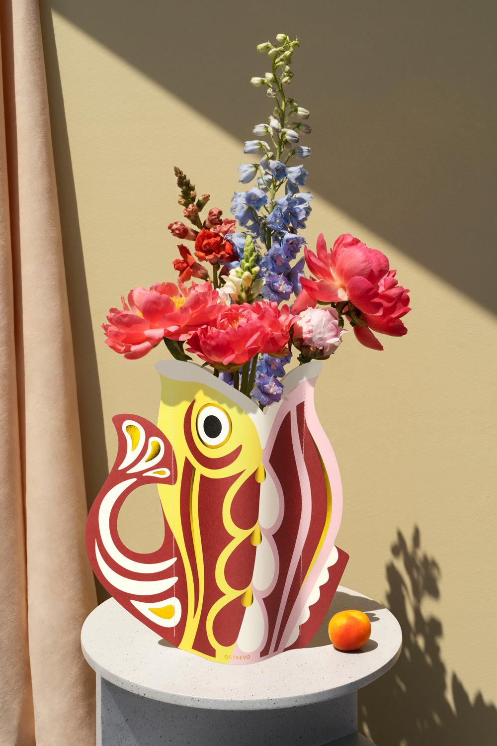 Decorative red OCTAEVO fish-shaped vase with colorful flowers. 