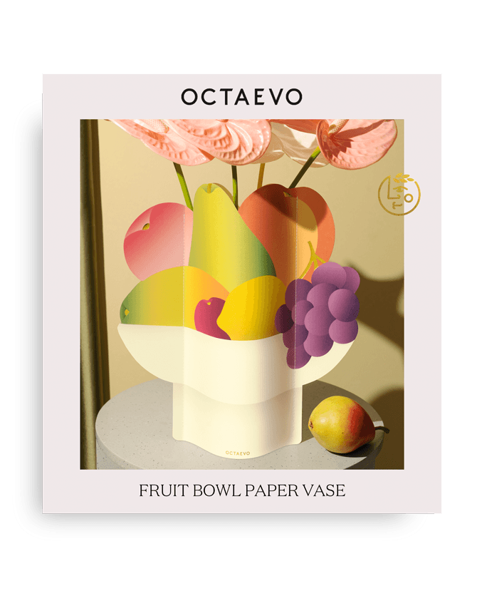 The Octaevo Fruit Bowl Paper Vase holds fruits as a centerpiece, with a pear beside it, displayed on a table.