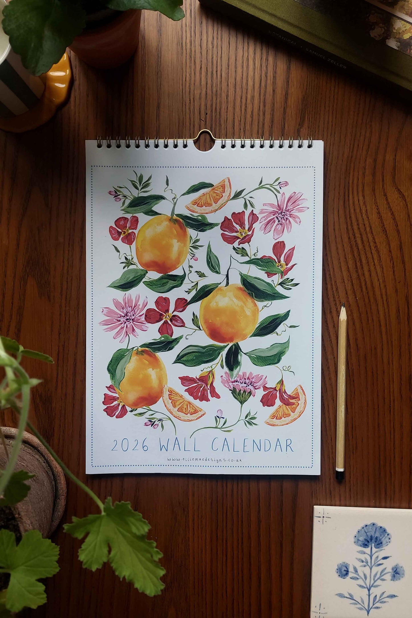 2026 wall calendar with floral and fruit design on a wooden surface