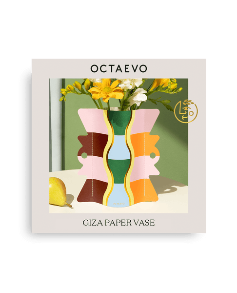 OCTAEVO Giza Mini Paper Vase with yellow flowers, pear, and sunlight casting shadows on a green background.