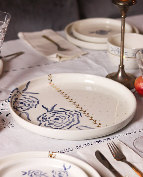 Ceramic plates with floral designs on a table setting with cutlery and glasses.