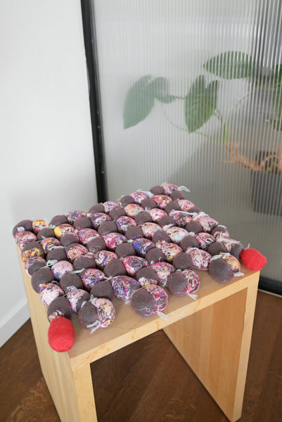 side view of hand-knotted knit seat cushion with transparent cover filled with upcycled materials on display