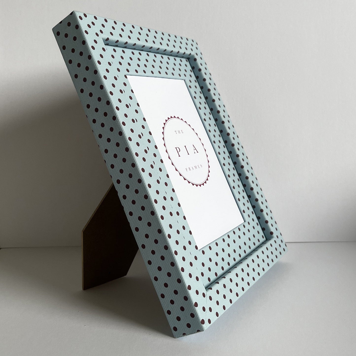 Angled view of handmade blue and burgundy Pembroke polka dot picture frame, showcasing the frame on a stand