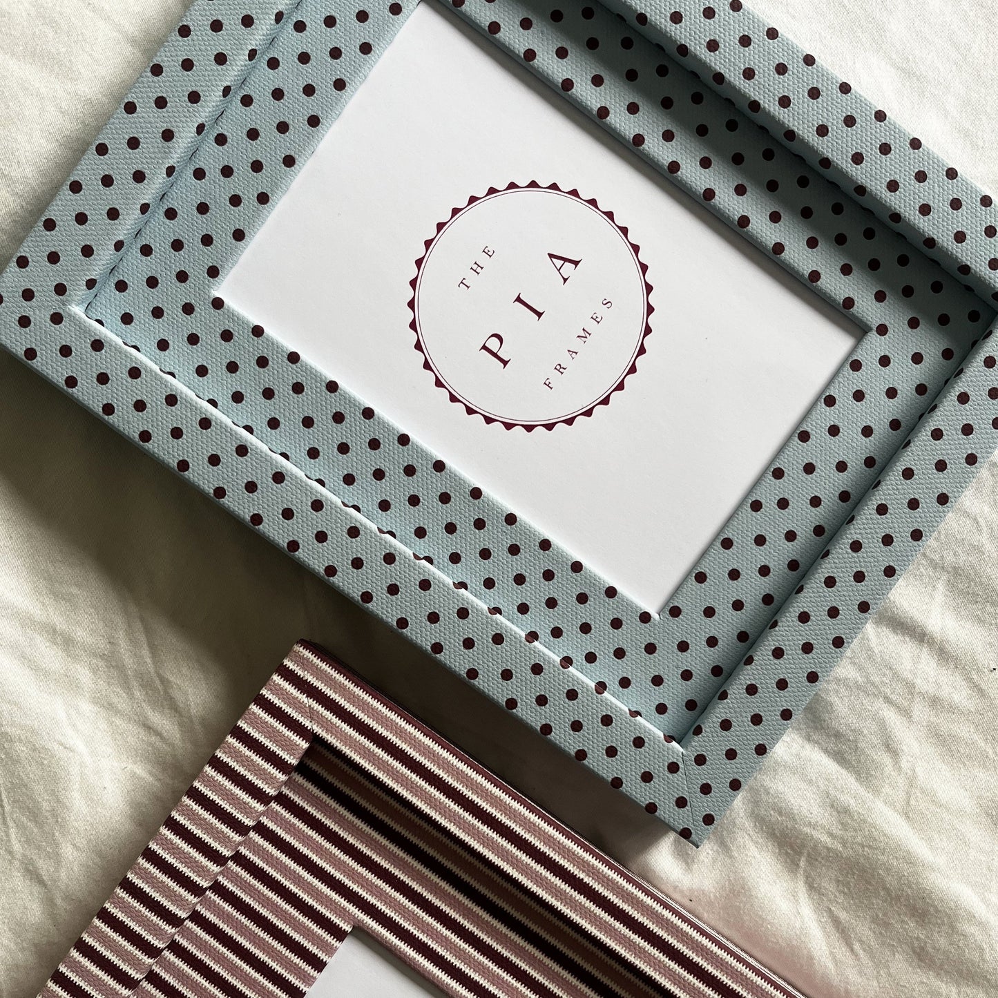 Set of handmade blue polka dot and burgundy blush stripe picture frames on a neutral background