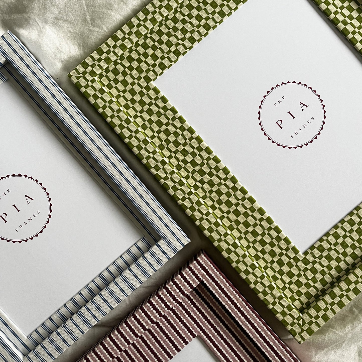 Set of three handmade colourful fabric picture frames on a white fabric background