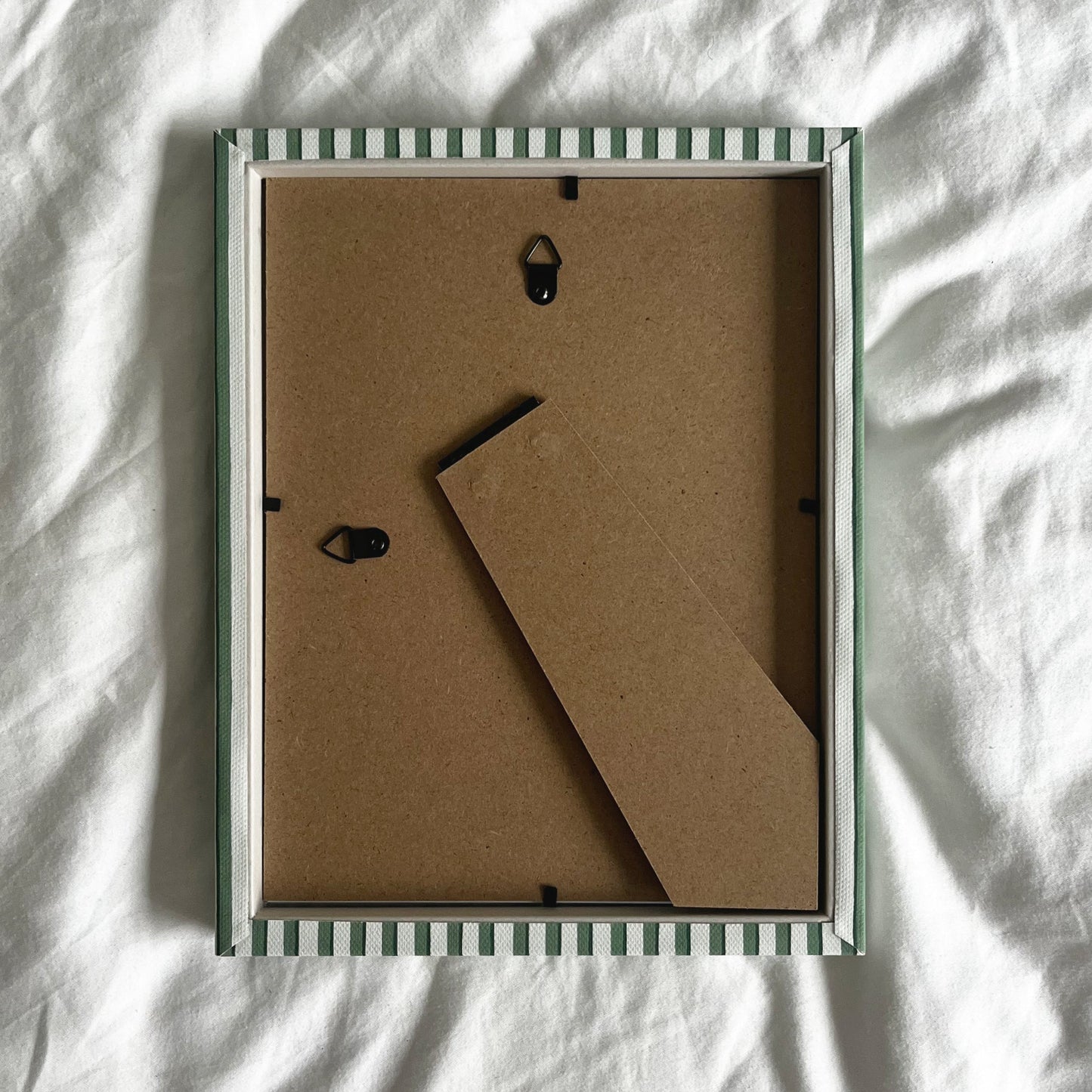 Back view of handmade green vanguard stripe picture frame, showing wall fittings and frame structure