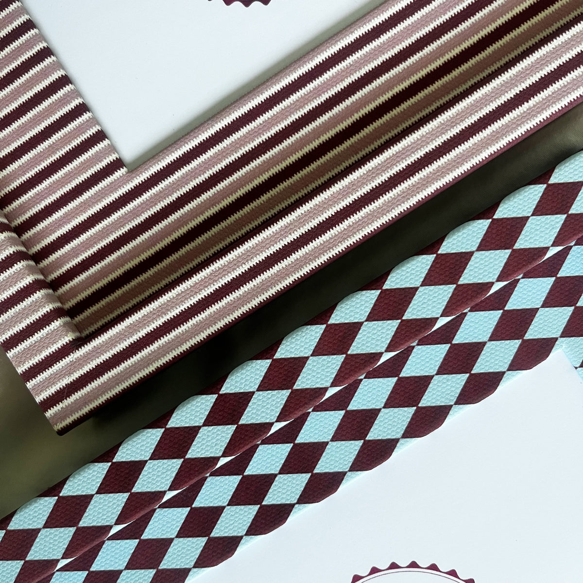 Set of burgundy harlequin and pink striped photo frame arranged on fabric