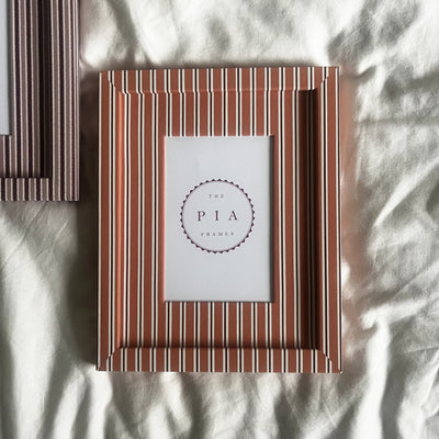 Pairing of handmade orange stripe and blush zigzag picture frames on a neutral background