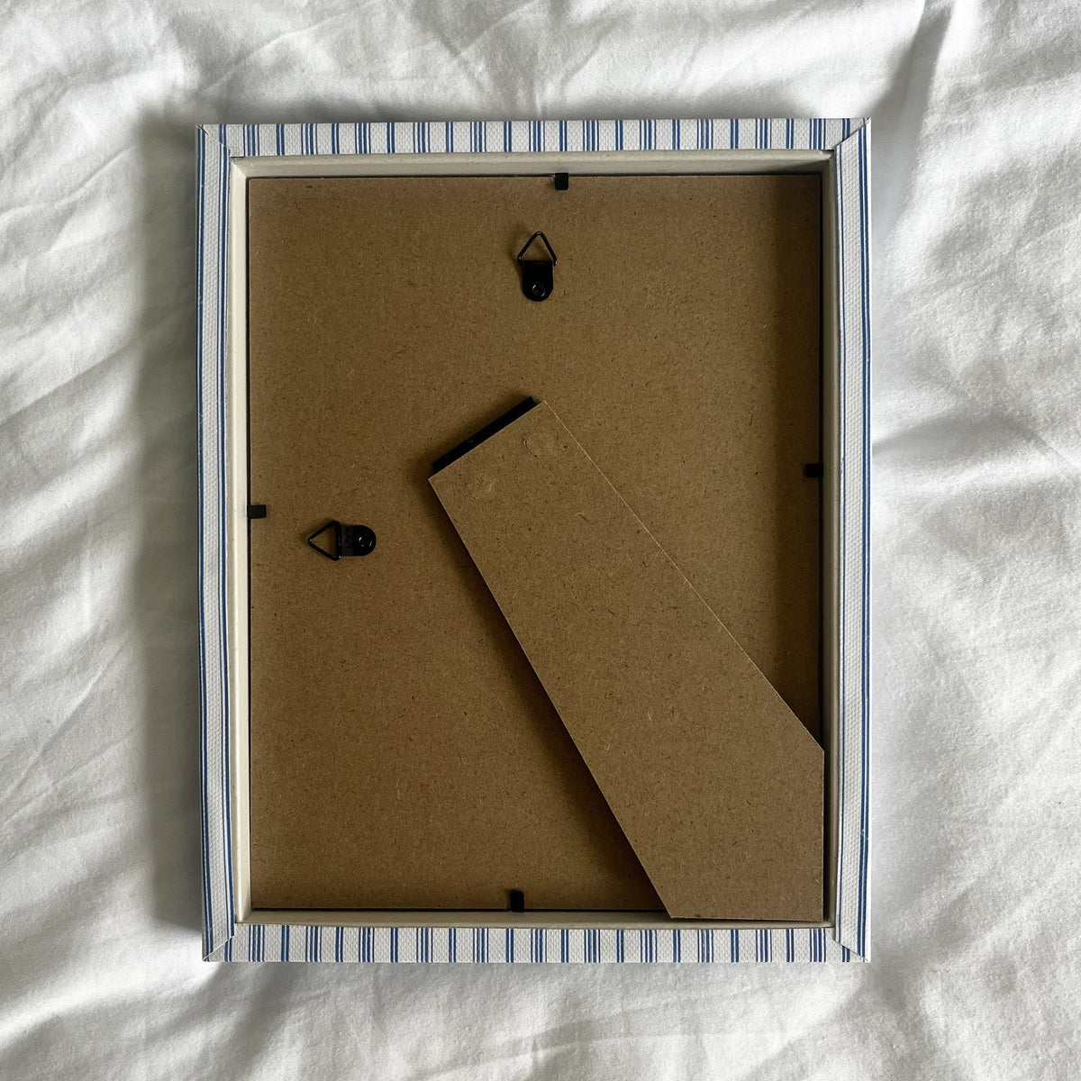 Back view of rustic blue striped picture frame, showing wall fittings and frame structure
