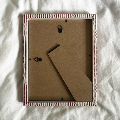 Back view of terracotta and beige striped picture frame, showing wall fittings and frame structure