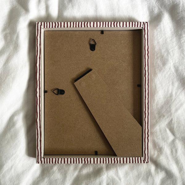 Back view of terracotta and beige striped picture frame, showing wall fittings and frame structure
