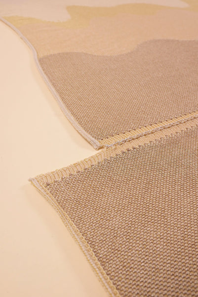 bottom detail of organic cotton knit tablecloth with hand-stitched seam in yellow monochrome tones