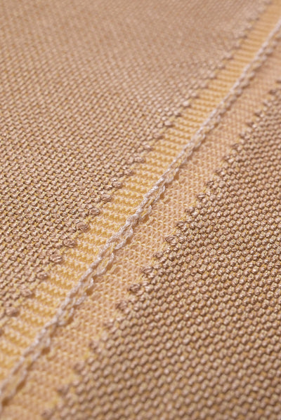 close-up detail of organic cotton knit tablecloth with hand-stitched seam in yellow monochrome tones