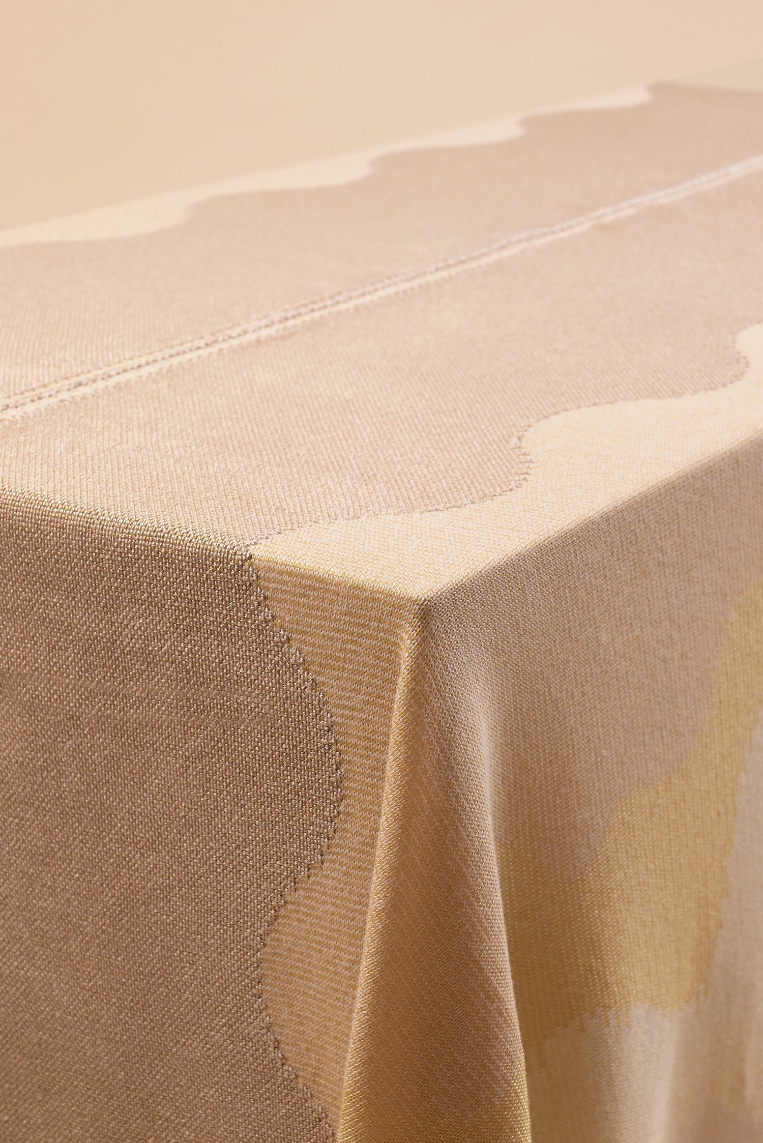 detail of organic cotton knit tablecloth with hand-stitched seam in yellow monochrome tones