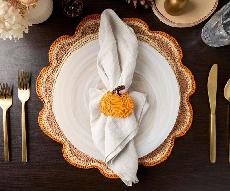 Overhead view of a fall place setting with a pumpkin napkin ring and gold flatware