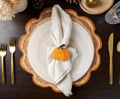 Overhead view of a fall place setting with a pumpkin napkin ring and gold flatware