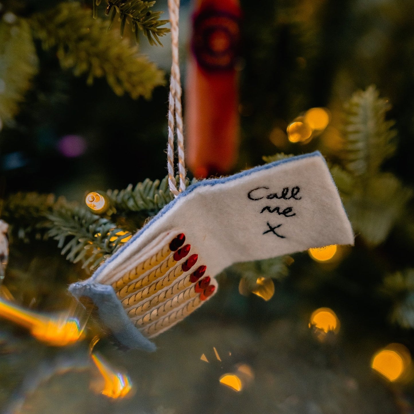 A matchbook embroidered and sequin ornament on a tree
