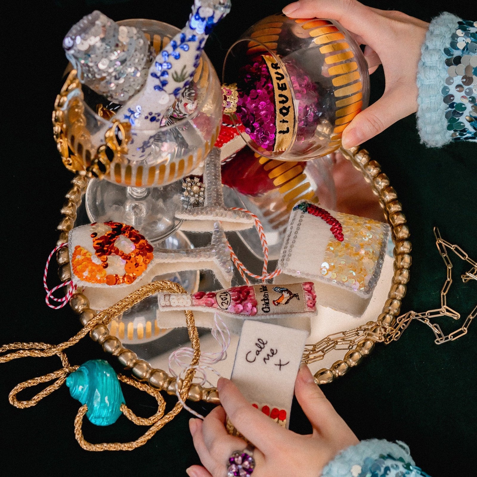 A collection of sequinned ornaments on a mirror with a woman's hands holding them