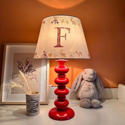 Empire lampshade for kids bedroom with woodland animals and personalised initial, lit to show warm kids lighting. A colourful lampshade and personalised kids gift perfect for bedtime reading.