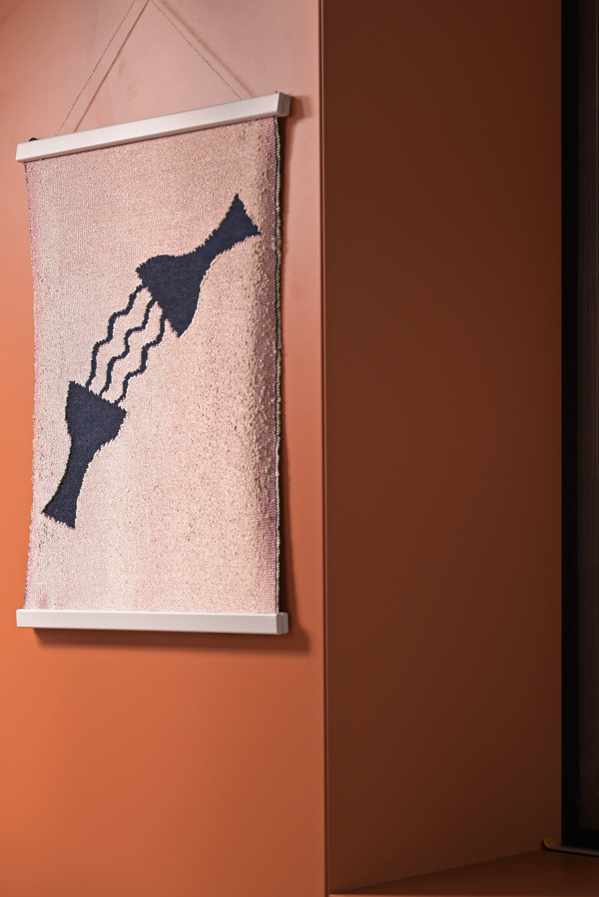 side view of pink knit wall hanging in with wooden magnetic frame displayed
