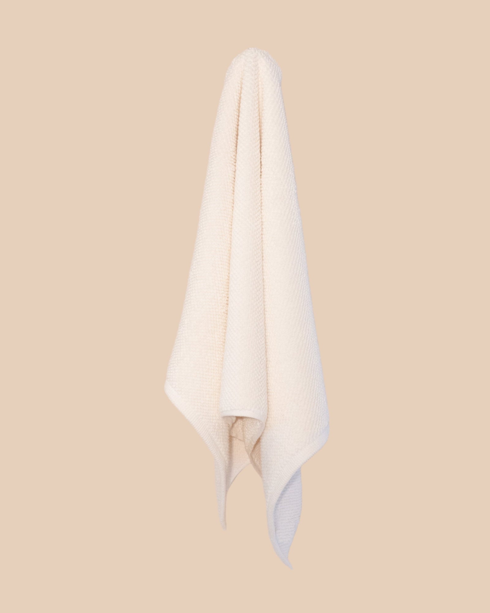 White hand  towel hanging against a beige background
