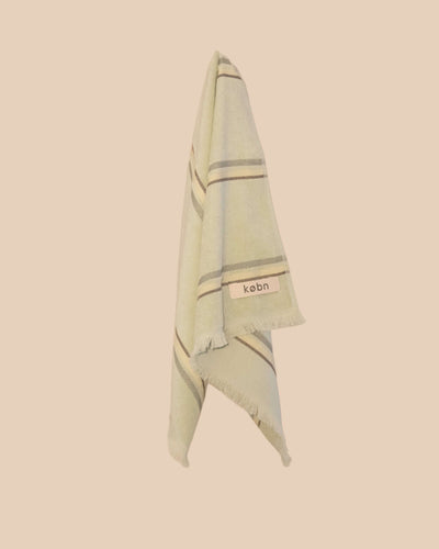 Light green hand towel with striped pattern and 'kebn' label on a beige background