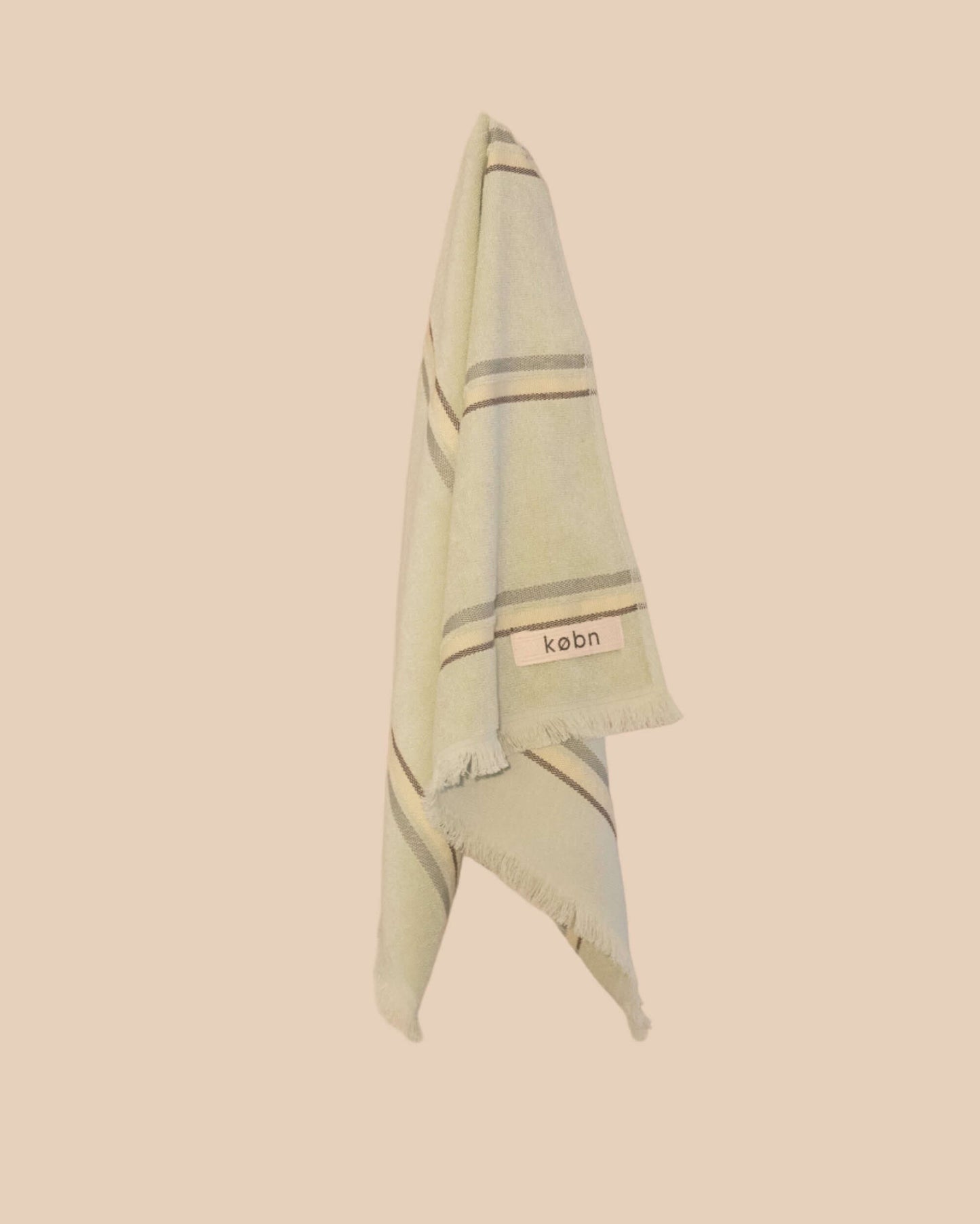 Light green hand towel with striped pattern and 'kebn' label on a beige background
