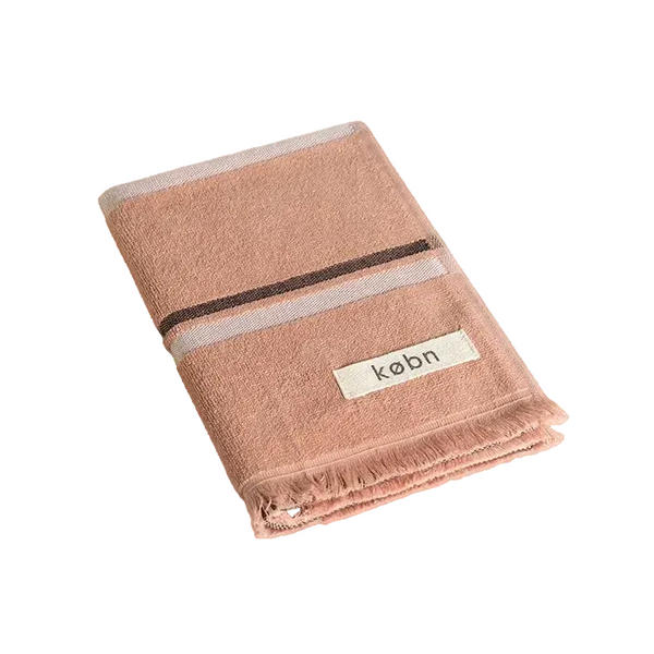 Folded Clay coloured hand towel with black and cream stripes and raw edge fringing. 